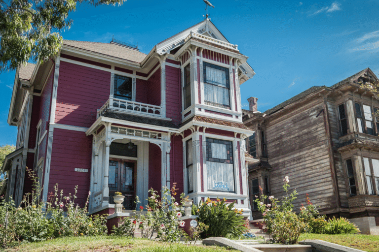 Maison victorienne rose avec jardin fleuri.