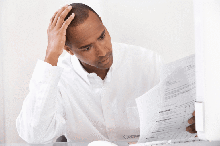Homme perplexe lisant des documents au bureau.