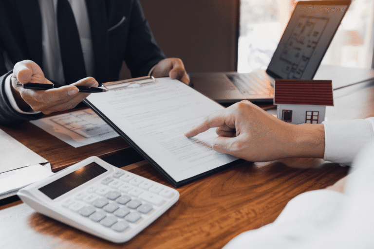 Consultation immobilière avec documents et maquette de maison.