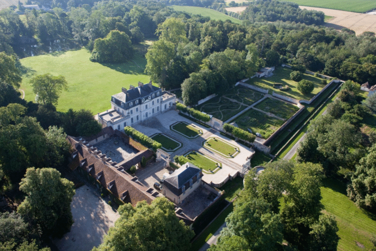 Château entouré de verdure et de jardins organisés.
