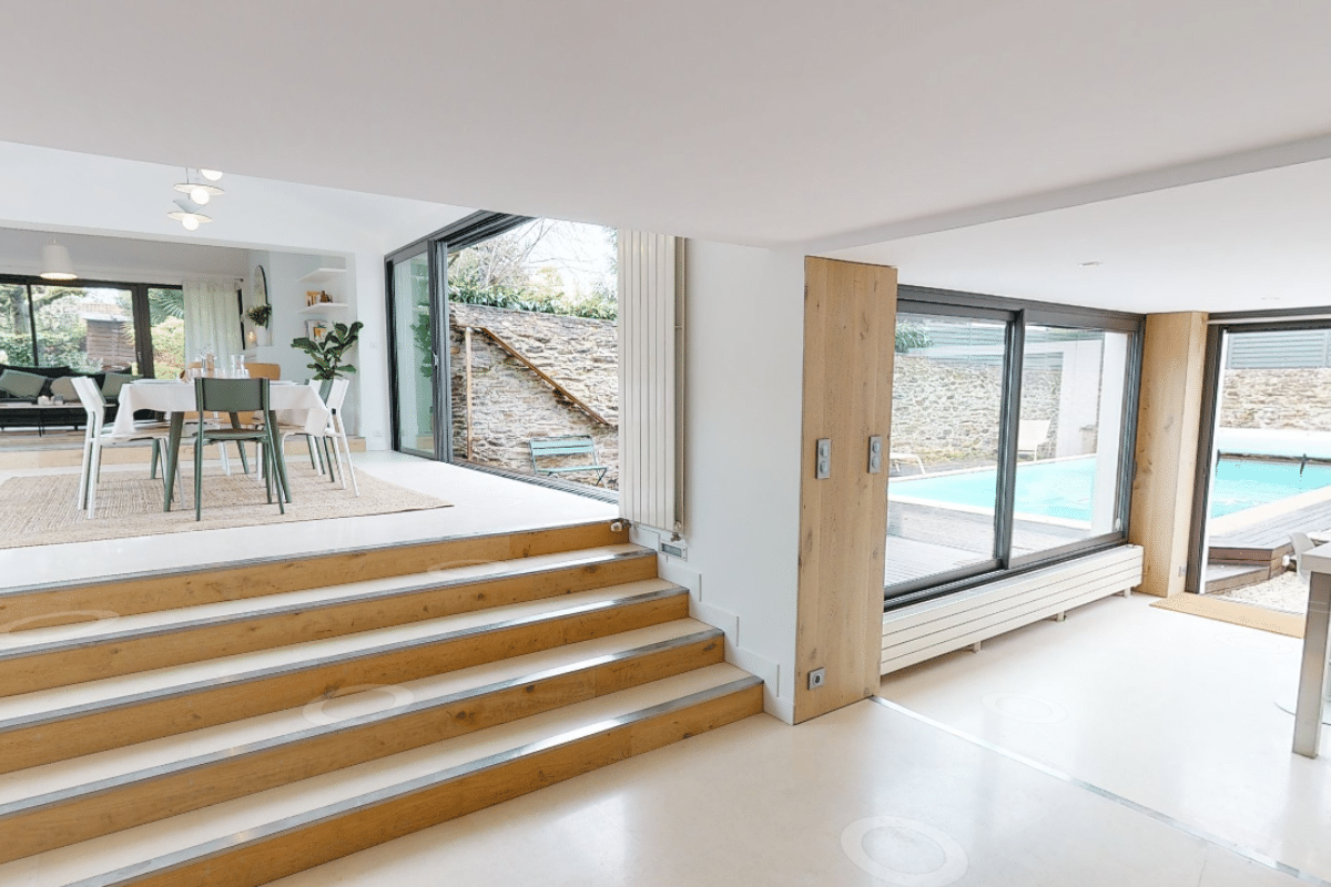 Intérieur moderne avec escalier et vue sur piscine.