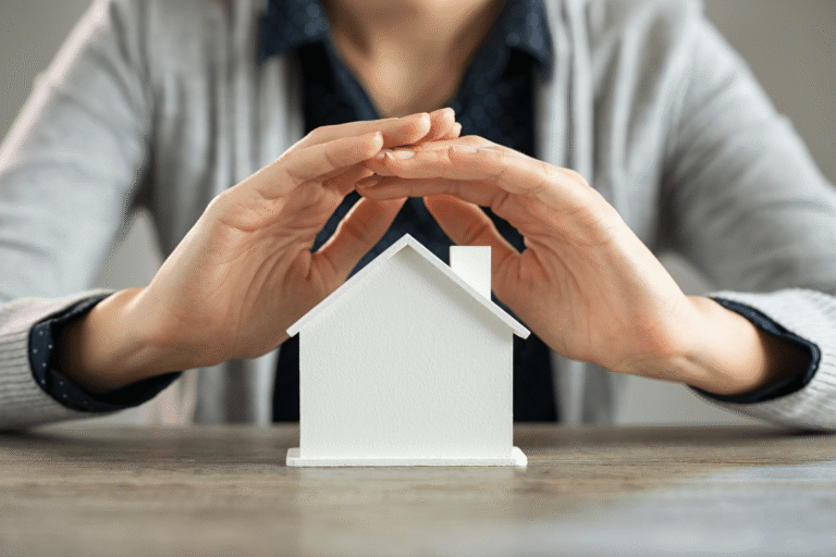 Mains protégeant une petite maison en modèle.