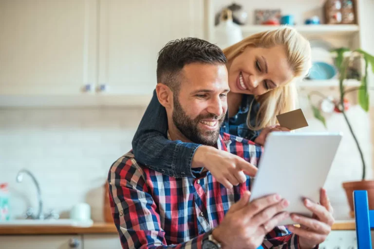 Couple souriant utilisant une tablette pour des achats en ligne.