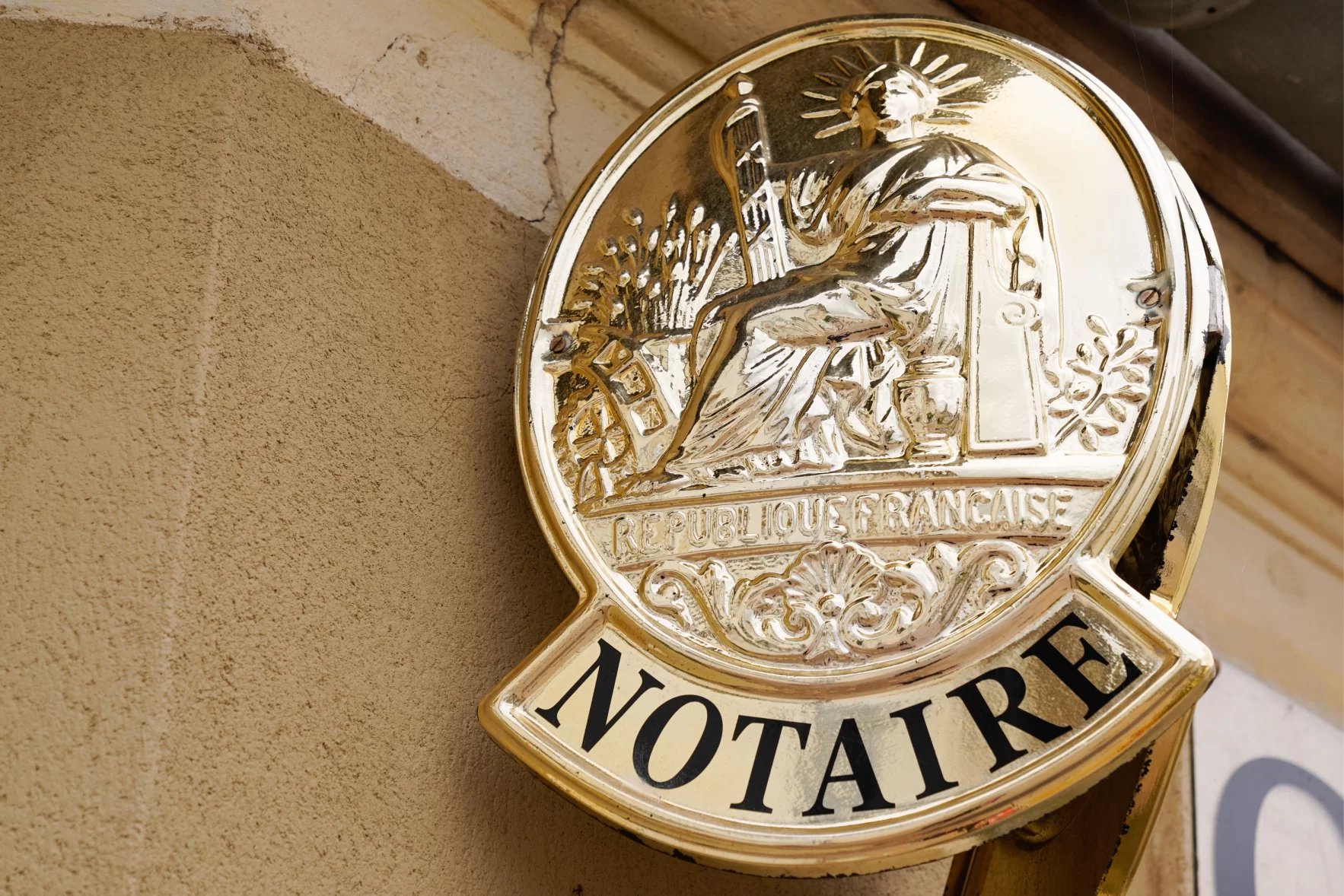Plaque dorée avec inscription "Notaire" et symbole de la République Française.