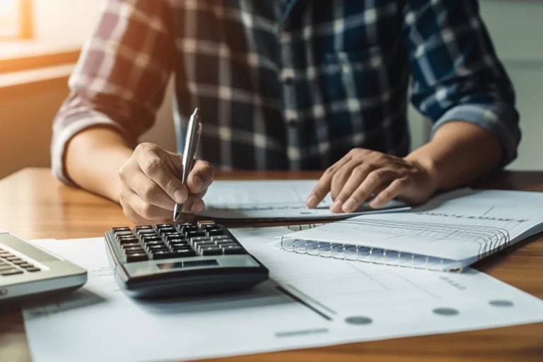 Personne écrivant avec un stylo près d'une calculatrice.