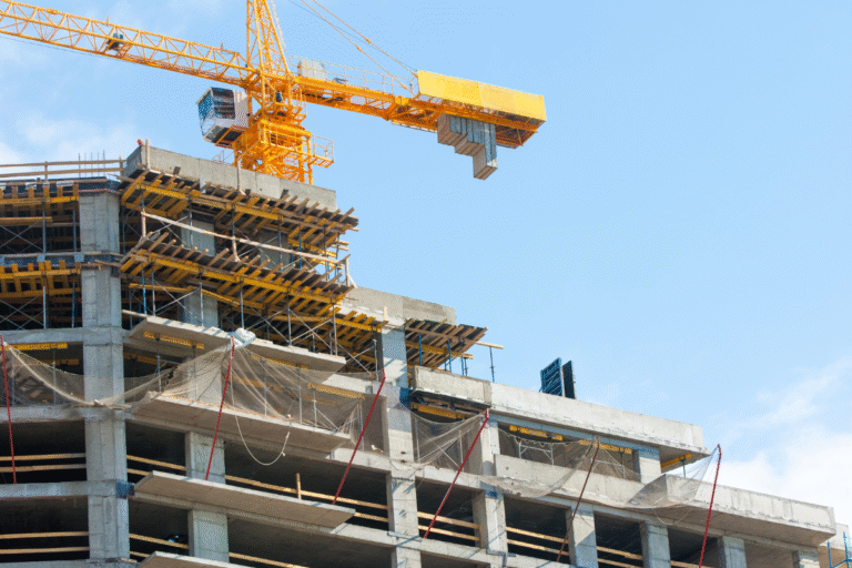 Grue jaune sur un bâtiment en construction sous un ciel bleu.