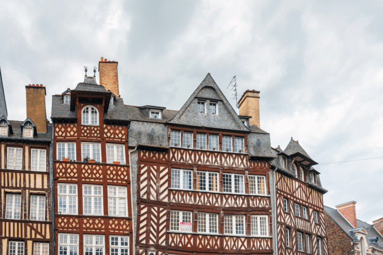 Maisons à colombages sous un ciel nuageux.
