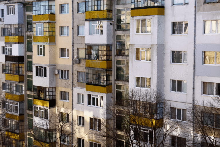 Façade d'immeuble avec balcons en verre et couleurs variées.