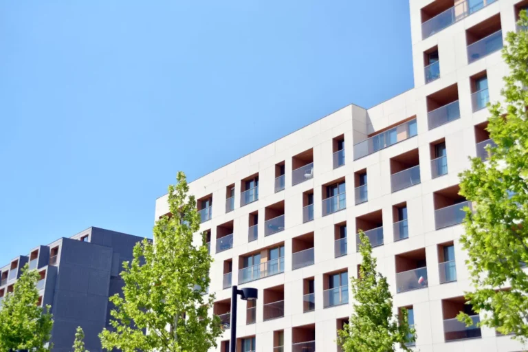Immeuble moderne avec balcons et arbres en façade.