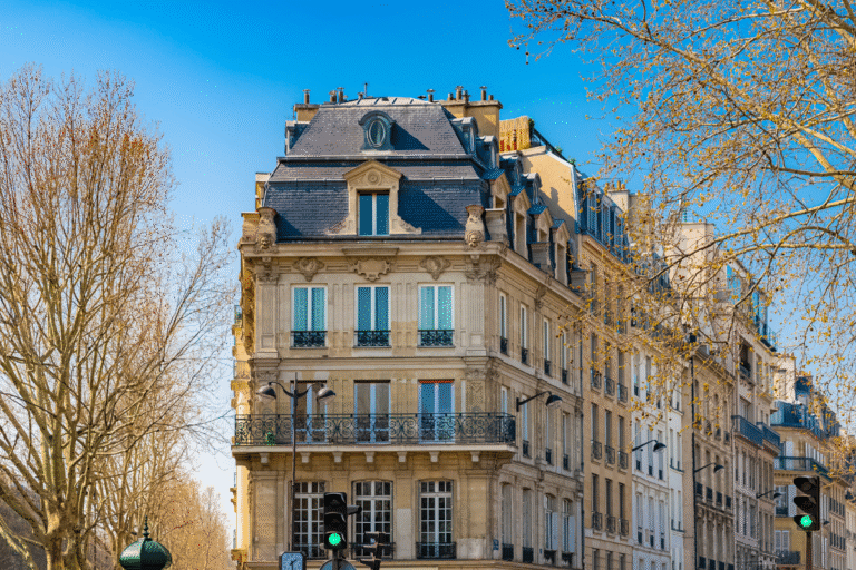 Bâtiment haussmannien avec balcons et arbres.