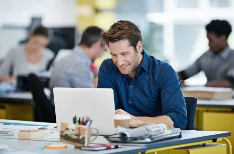 Homme souriant travaillant sur un ordinateur portable.