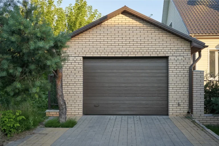 Garage en briques claires avec porte grise.