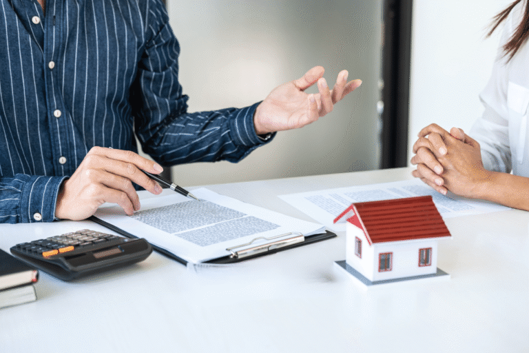 Discussion sur l'achat immobilier avec documents et maquette de maison.