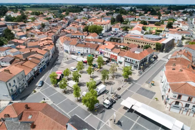 Vue aérienne d'une place bordée de bâtiments à toit rouge.