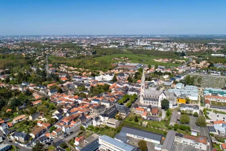 Vue aérienne d'un quartier résidentiel avec église et champs.