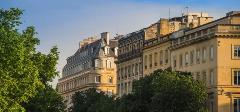 Façades architecturales historiques avec végétation en avant-plan.