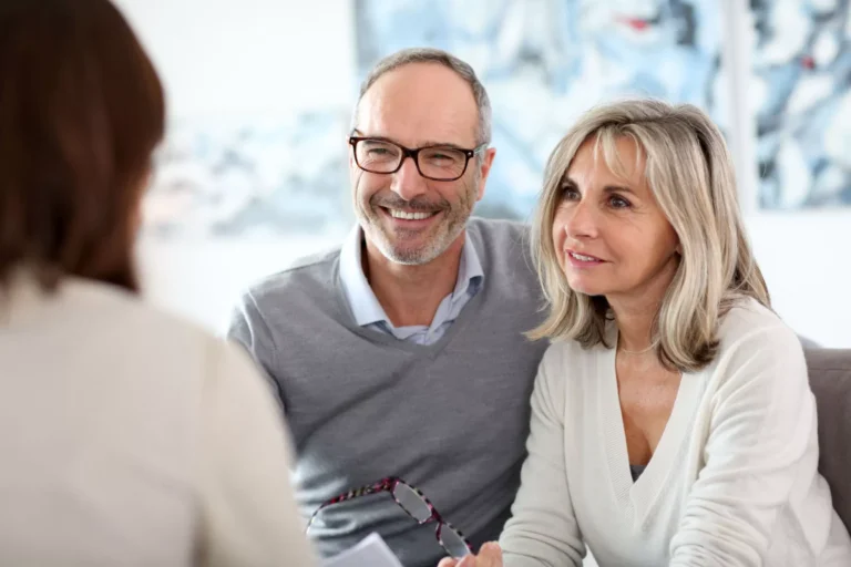 Couple souriant en discussion avec un conseiller.