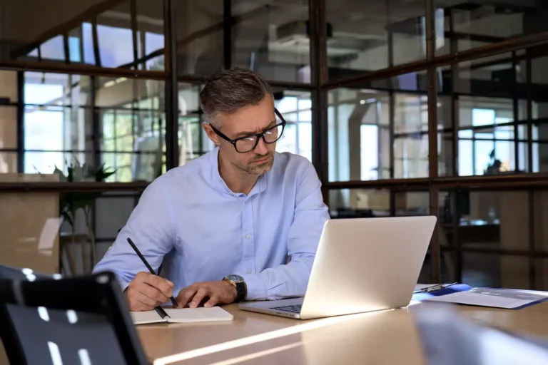 Homme en chemise bleue travaillant sur un ordinateur portable.