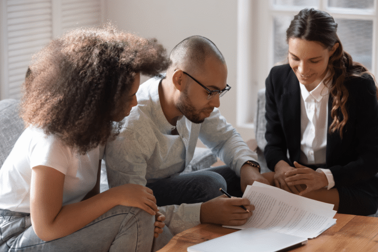 Trois personnes collaborent sur un document, sourire aux lèvres.