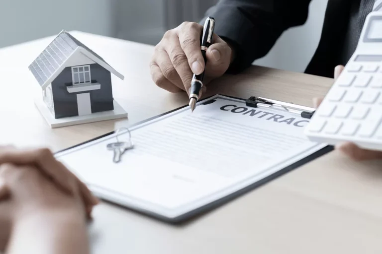 Signature d'un contrat immobilier avec une maison miniature.