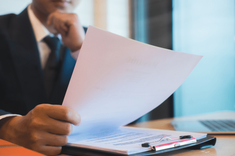 Homme en costume examine un document sur une table.