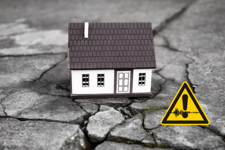 Maison miniature sur un sol fissuré avec un symbole de danger.