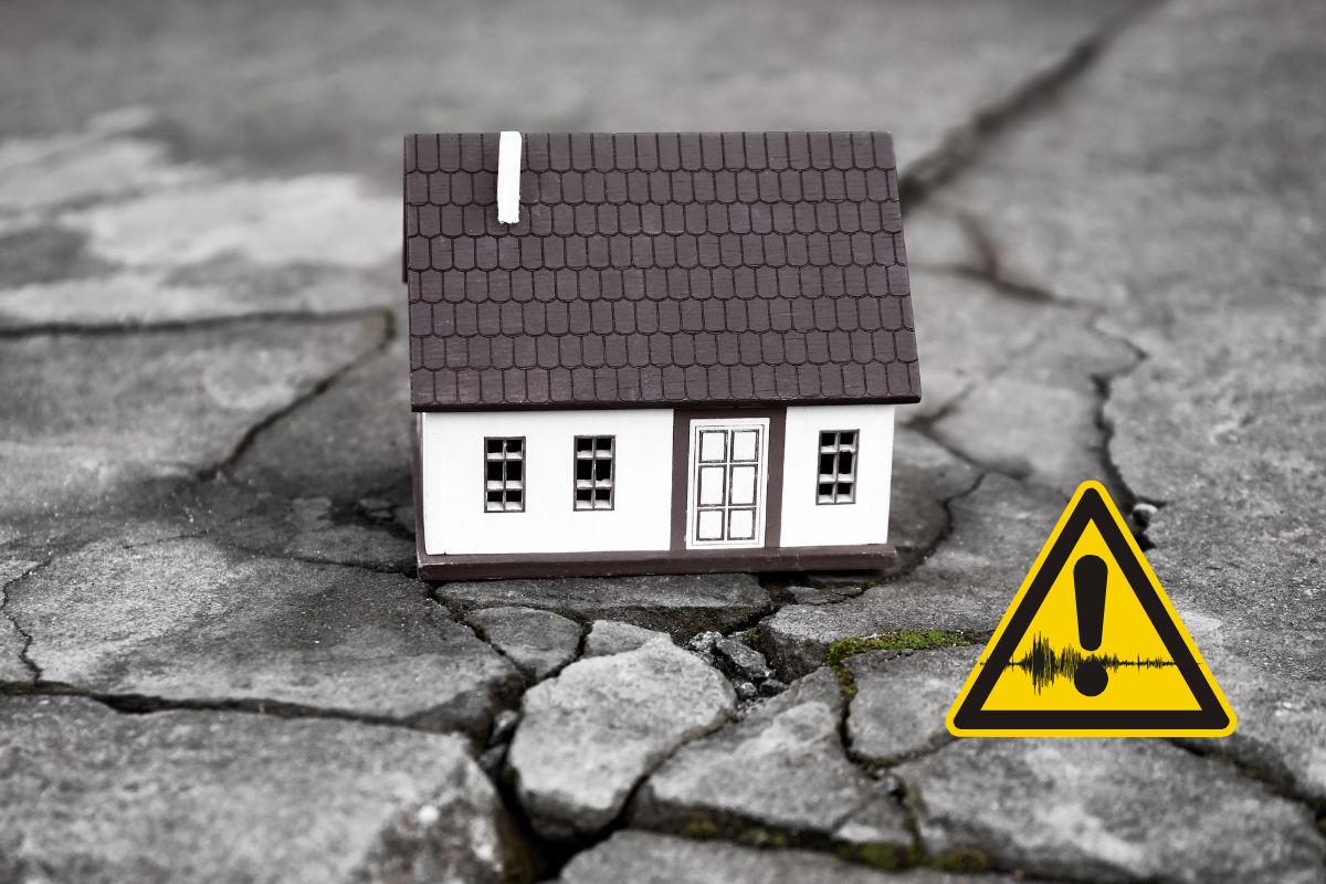 Maison miniature sur un sol fissuré avec un symbole de danger.