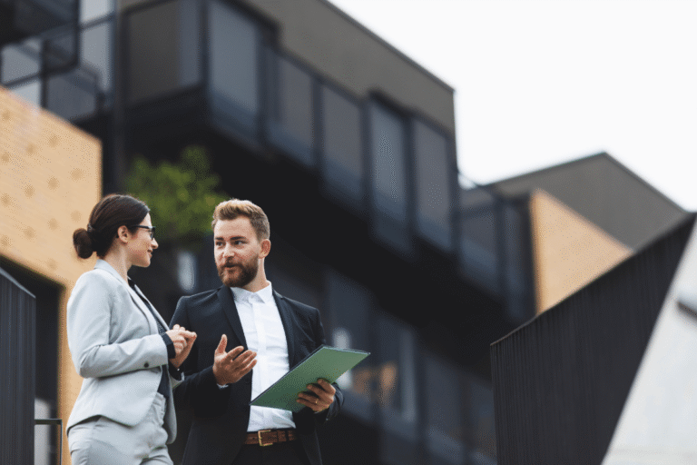 Deux professionnels discutent devant un bâtiment moderne.