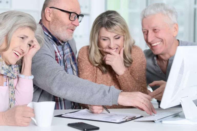 Groupe de seniors souriant autour d'un ordinateur.