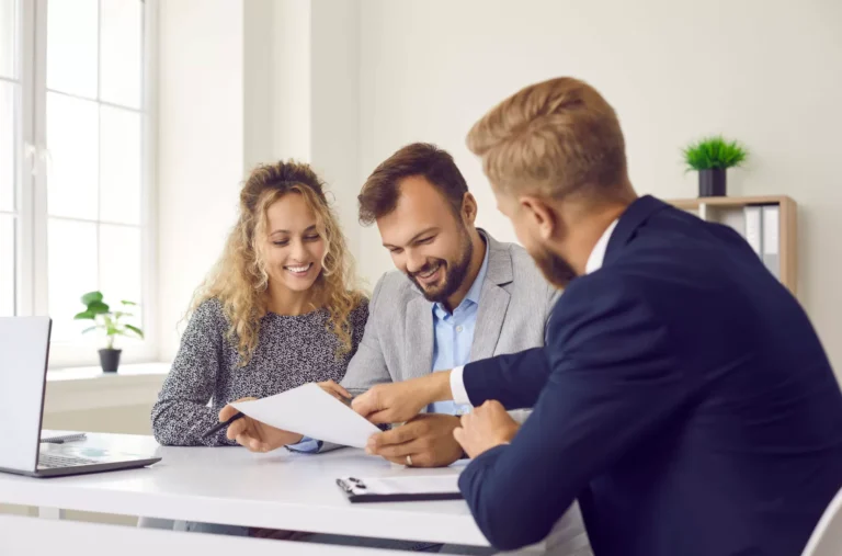 Trois personnes souriantes discutent autour d'une table.