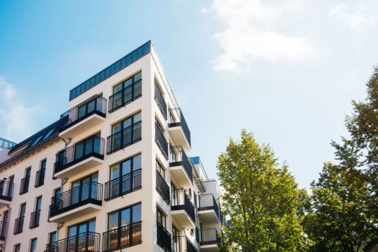 Immeuble moderne avec balcons et arbres verts.