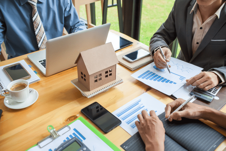 Réunion de travail avec graphiques et maquette de maison.
