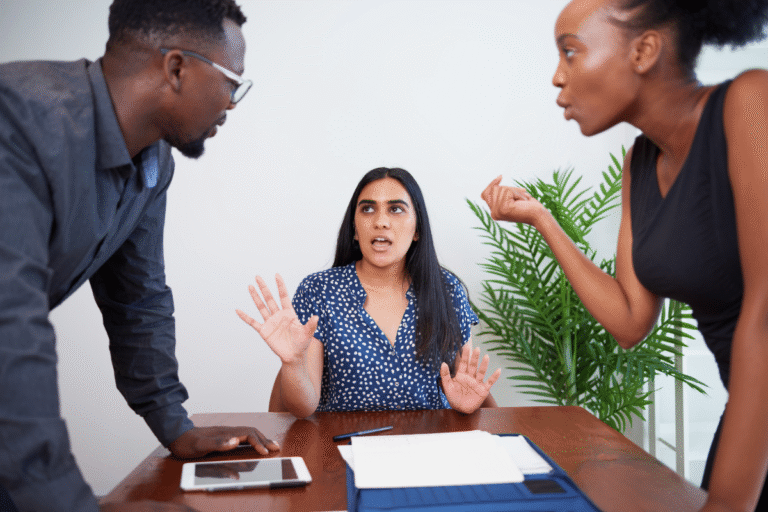 Discussion tendue entre trois personnes autour d'une table.
