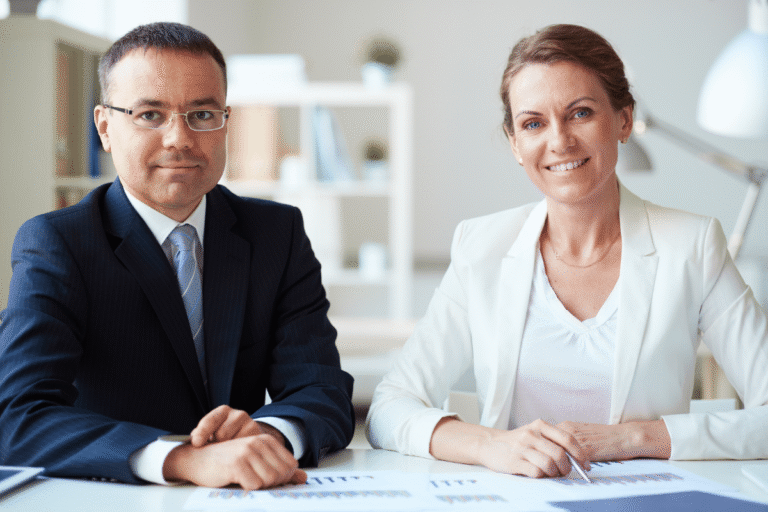 Professionnels en costume posant devant des documents de travail.