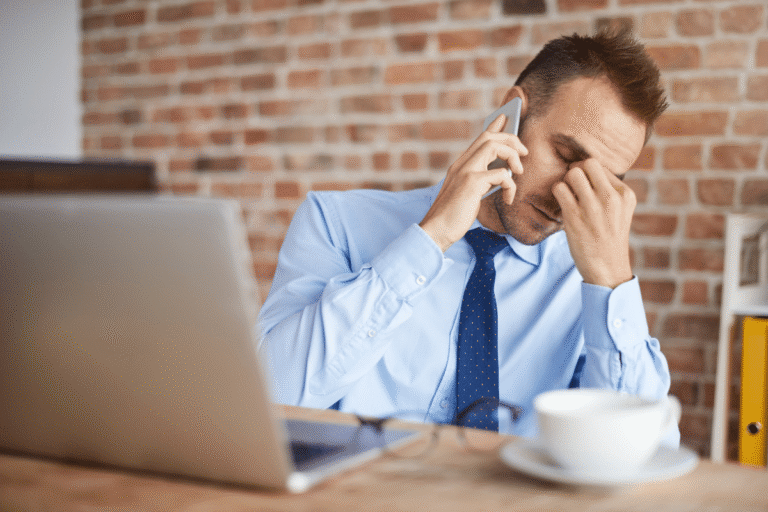 Homme en chemise bleue, au téléphone, visiblement stressé.