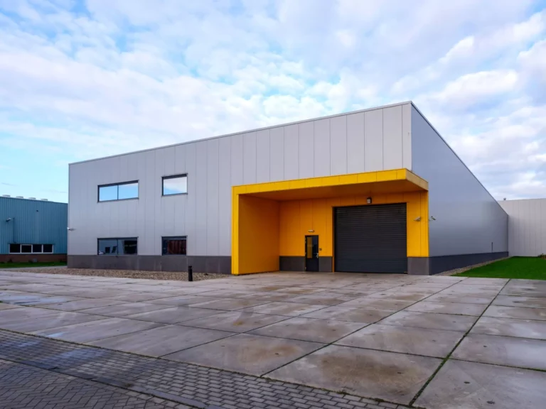 Bâtiment industriel avec façade grise et portail jaune.