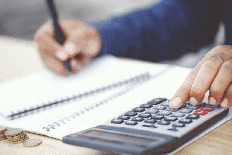 Main tenant un stylo et utilisant une calculatrice avec des pièces.