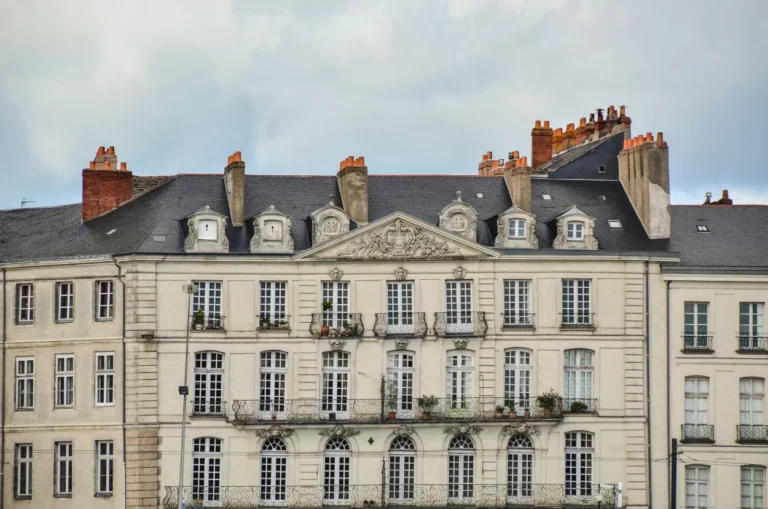 Façade d'immeuble classique avec balcons fleuris.