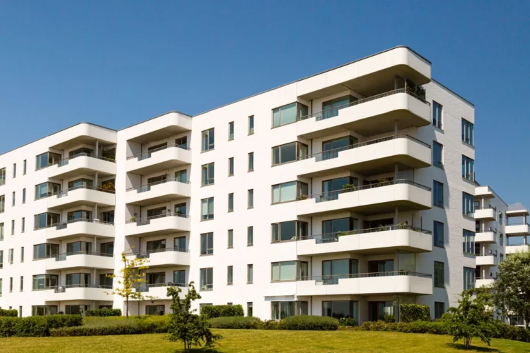 Immeuble moderne avec balcons et façade blanche.