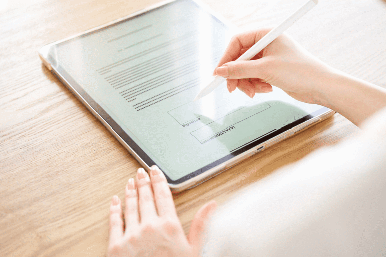 Main tenant un stylet, remplissant un formulaire sur une tablette.