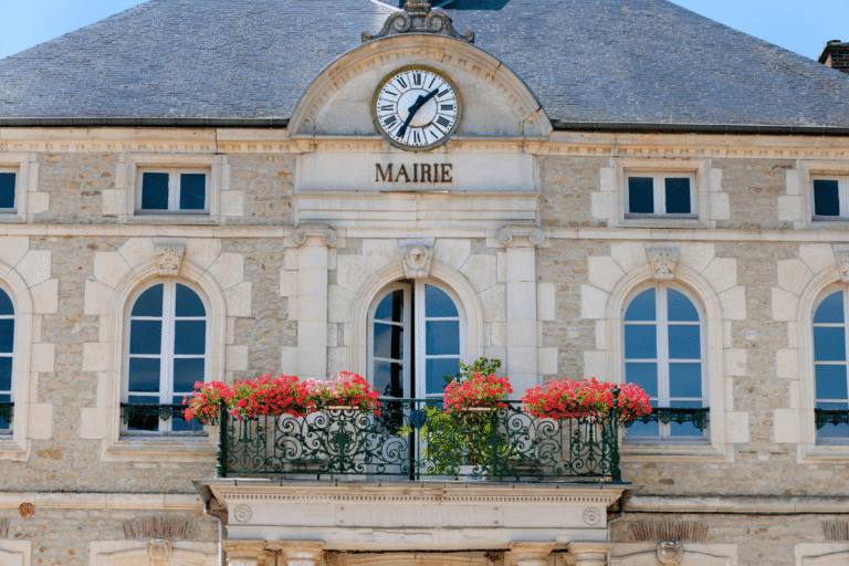 Façade de mairie avec horloge et fleurs colorées.