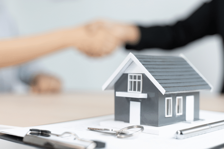 Maison miniature sur un contrat avec des mains se serrant.