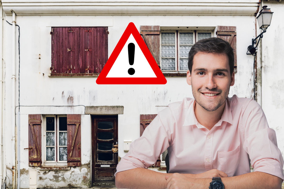 Homme souriant devant une maison avec des volets en bois, panneau d'avertissement visible.