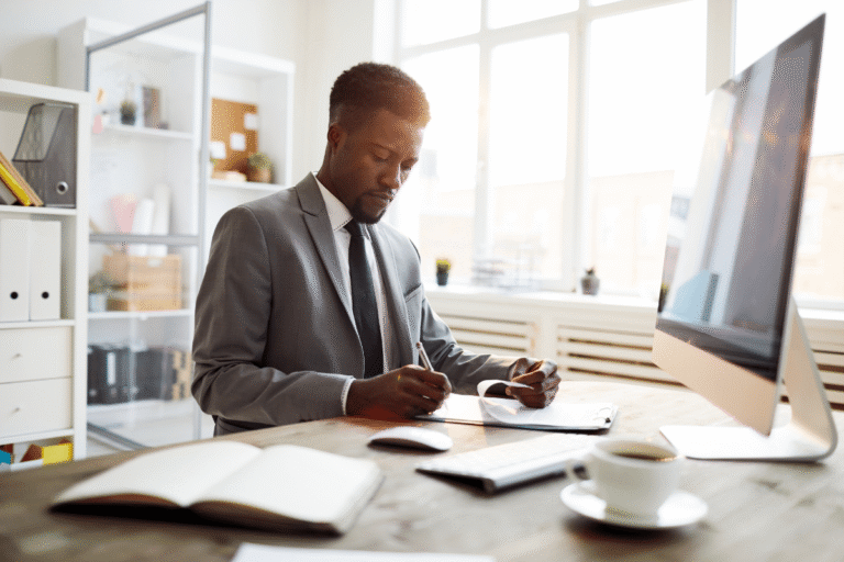 Homme en costume prenant des notes au bureau.